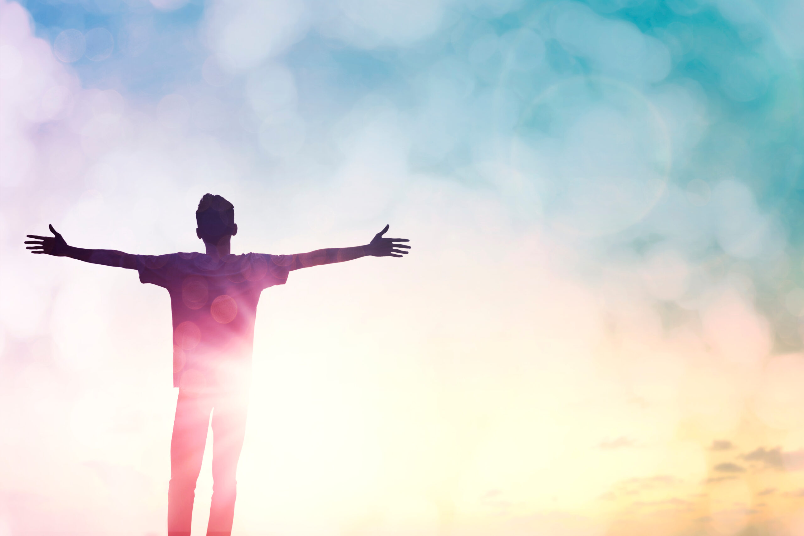 a man raising his hands in praise before the rising sun